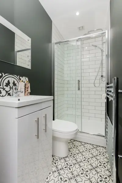 Bathroom with shower enclosure, toilet, vanity unit and patterned floor tiles