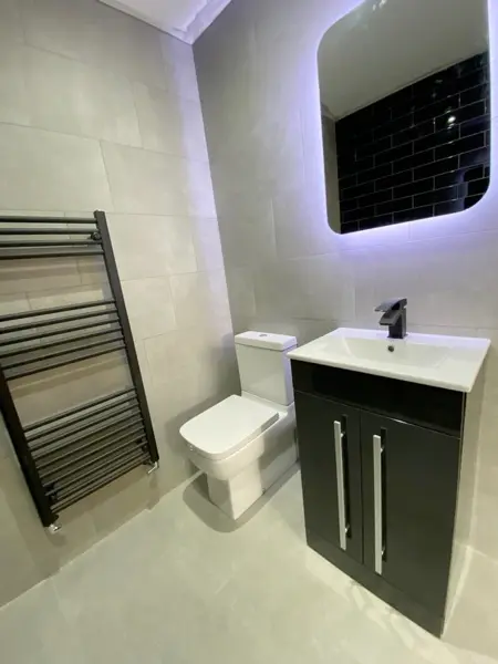 Modern bathroom with heated towel rail, toilet and dark vanity unit