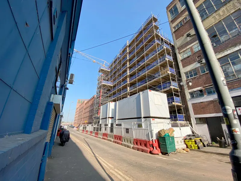 Scaffolded apartment block under construction on a city street
