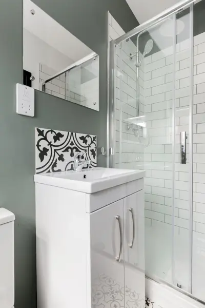 Shower room with glass shower door, vanity unit and patterned tiles